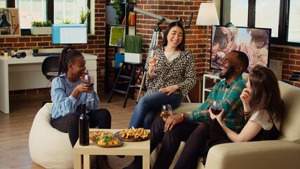 Diverse group friends celebrating asian woman birthday, drinking alcoholic beverages and eating appetizers in living room. Happy guests laughing and discussing after gifting host presents