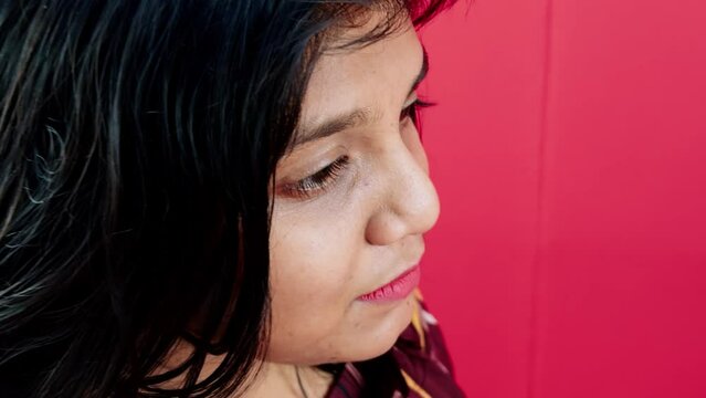 women face closeup thinking with smile against red background