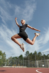 Sportive woman captures motion in mid-air jump during a dynamic workout at a basketball court
