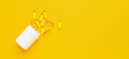 Bottle of fish oil capsules on yellow background with space for text, top view