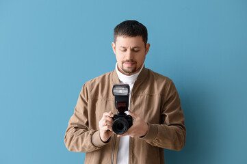 Male photographer with professional camera on blue background