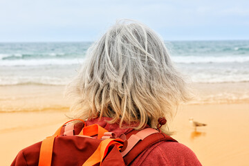 Rear view of silver haired woman looking out to sea