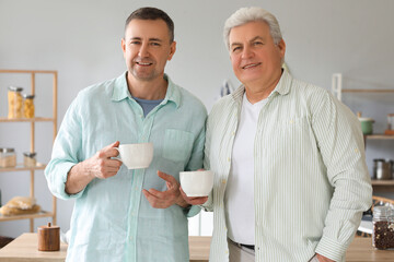 Mature brothers drinking tea in kitchen