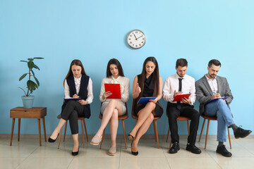 Young people with clipboards waiting for job interview in room