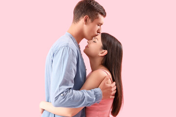 Happy young couple kissing on pink background