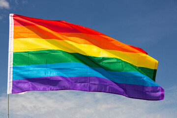 Huge flag of LGBT attached on long handle against background of clear bright sky
