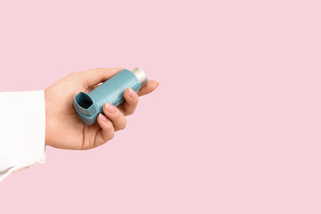 Female doctor hand with inhaler on pink background