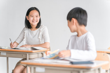 学校の教室で楽しく勉強する笑顔の女子小学生（塾・夏期講習）
