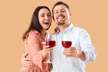 Happy young couple with glasses of wine on beige background