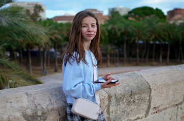Portrait of a young girl with mobile phone on the background of palm trees