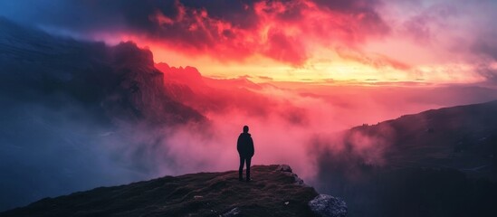 Man witnessing a colorful autumn sunset at Dolomites Landscape, surrounded by foggy hills and a beautiful dusk sky in the Alps. - obrazy, fototapety, plakaty