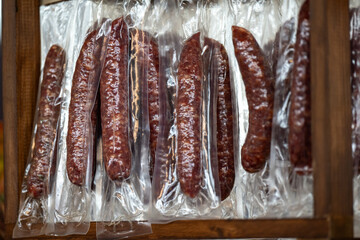 Multiple pieces of wrapped cured pepperoni sticks. The vacuum pack smoky red 100% natural protein...