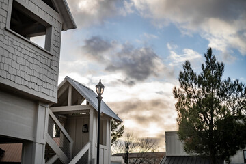 Rooftops Small Buildings With Lamp Light Partially Cloudy Blue Sky Treetops