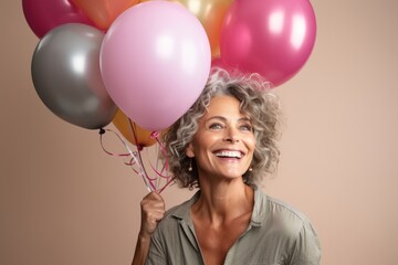 Portrait of a happy senior woman holding balloons, looking up and smiling