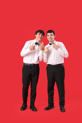 Married gay couple pointing at wedding rings on red background