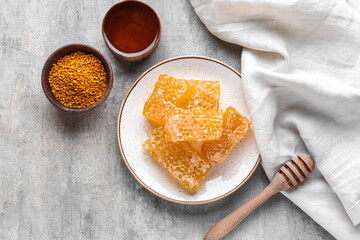 Plate with sweet honeycombs on grey background