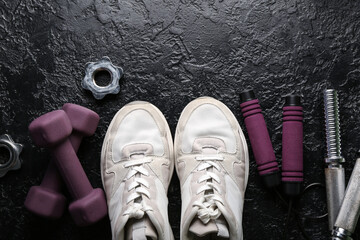 Dumbbells, shoes, clamps, skipping rope and grips on black background