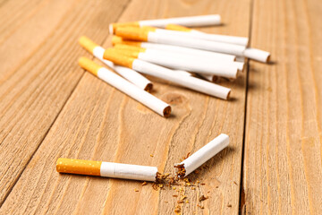 Cigarettes with scattered tobacco on wooden background, closeup. Lung cancer concept