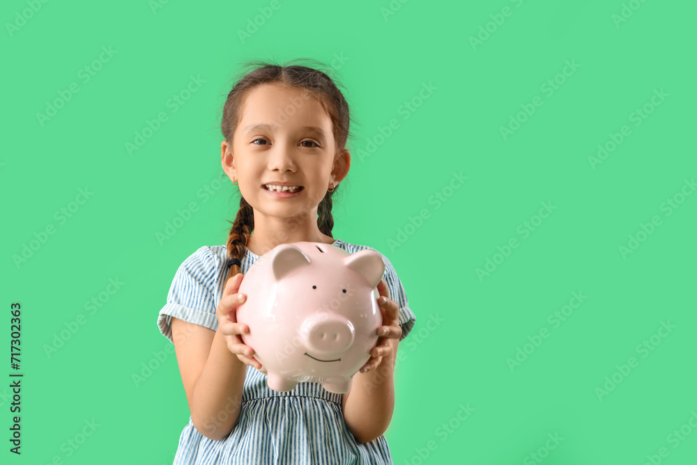 Sticker little girl with piggy bank on green background