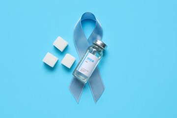 Awareness ribbon with insulin and sugar cubes on blue background. Diabetes concept