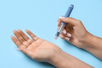 Woman with lancet pen on blue background. Diabetes concept