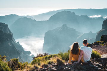 Tourist couple enjoys the panoramicview from the mountain top of a volcanic island on a sunny...