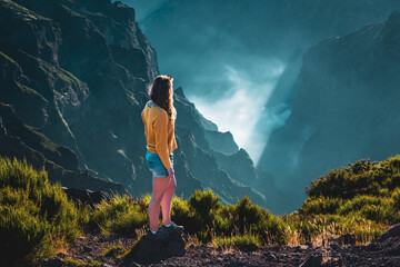 Athletic female tourist overlooks the breathtaking depths of a cloud-covered valley and enjoys the...