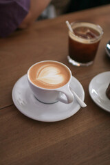 Hot Latte espresso coffee with heart shape latte art in white ceramic cup serve with bakery on wooden table.  Morning breakfast.
