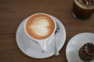 Hot Latte espresso coffee with heart shape latte art in white ceramic cup serve with bakery on wooden table.  Morning breakfast.