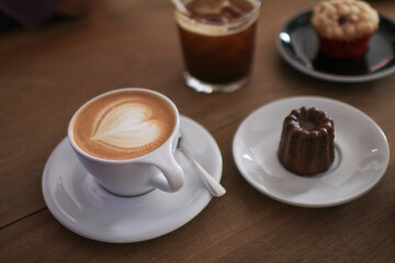 Hot Latte espresso coffee with heart shape latte art in white ceramic cup serve with bakery on wooden table.  Morning breakfast.