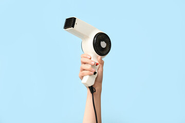 Female hand with hairdryer on color background.