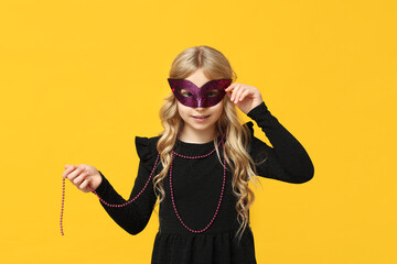 Pretty little girl wearing carnival mask on yellow background © Pixel-Shot