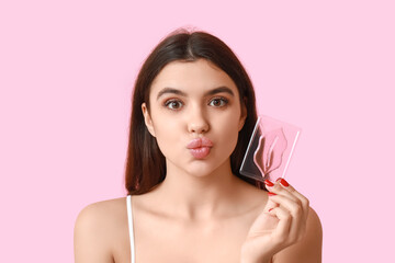Beautiful young woman with lip mask on pink background