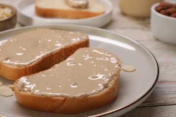 Toasts with tasty nut butter and almond flakes on wooden table, closeup
