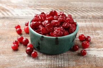 Tasty dried cranberries in bowl and fresh ones on rustic wooden table, closeup