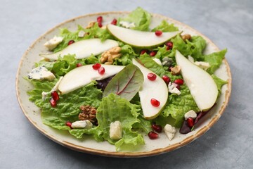 Plate with delicious pear salad on grey textured table, closeup