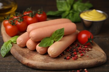 Delicious boiled sausages, tomatoes, basil and peppercorns on wooden table, closeup