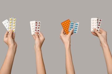 Female hands holding pills in blister packs on grey background