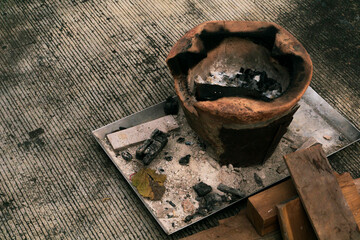 Burning charcoal in a clay pot on a wooden table with copy space