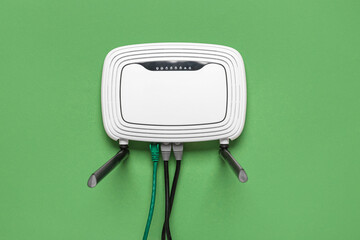 Modern wi-fi router with cables on green background