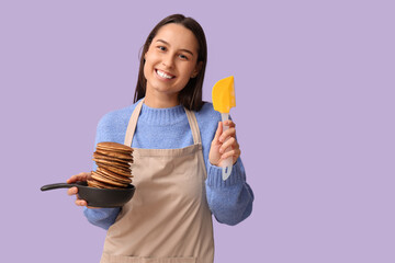 Beautiful young woman holding frying pan with tasty pancakes on lilac background