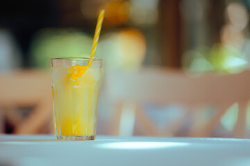 Glass of Lemonade with a Straw in a Restaurant during Summer. Composition with copy space of a summer refreshing beverage 
