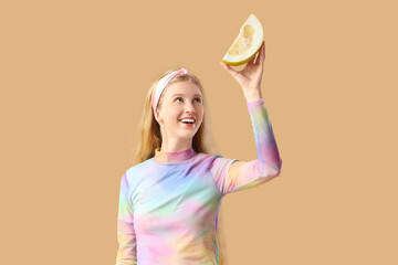 Young woman with pomelo piece on beige background