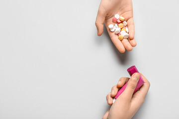 Child's hands with asthma inhaler and pills on white background
