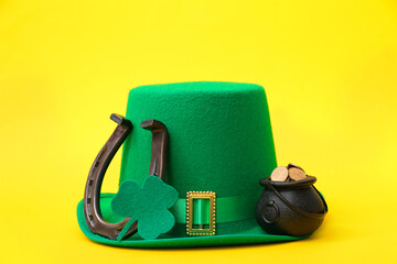 Pot with golden coins, leprechaun hat and horseshoe on yellow background. St. Patrick's Day...