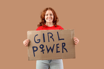 Beautiful young happy woman holding paper with text GIRL POWER on beige background. Women history...