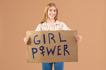 Beautiful young happy woman holding paper with text GIRL POWER on beige background. Women history...
