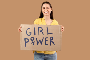 Beautiful young happy woman holding paper with text GIRL POWER on beige background. Women history...