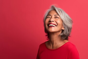 Obraz na płótnie Canvas Portrait of a happy senior woman on a red background. Portrait of a beautiful mature woman laughing