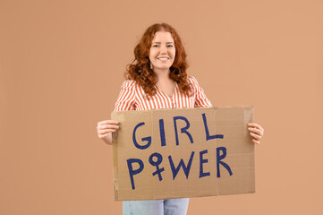 Beautiful young happy woman holding paper with text GIRL POWER on beige background. Women history...